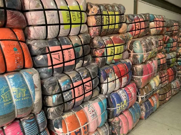 Warehouse wall stacked with colourful compressed clothing bales